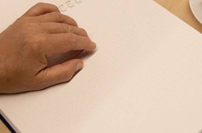 A hand on a page of braille
